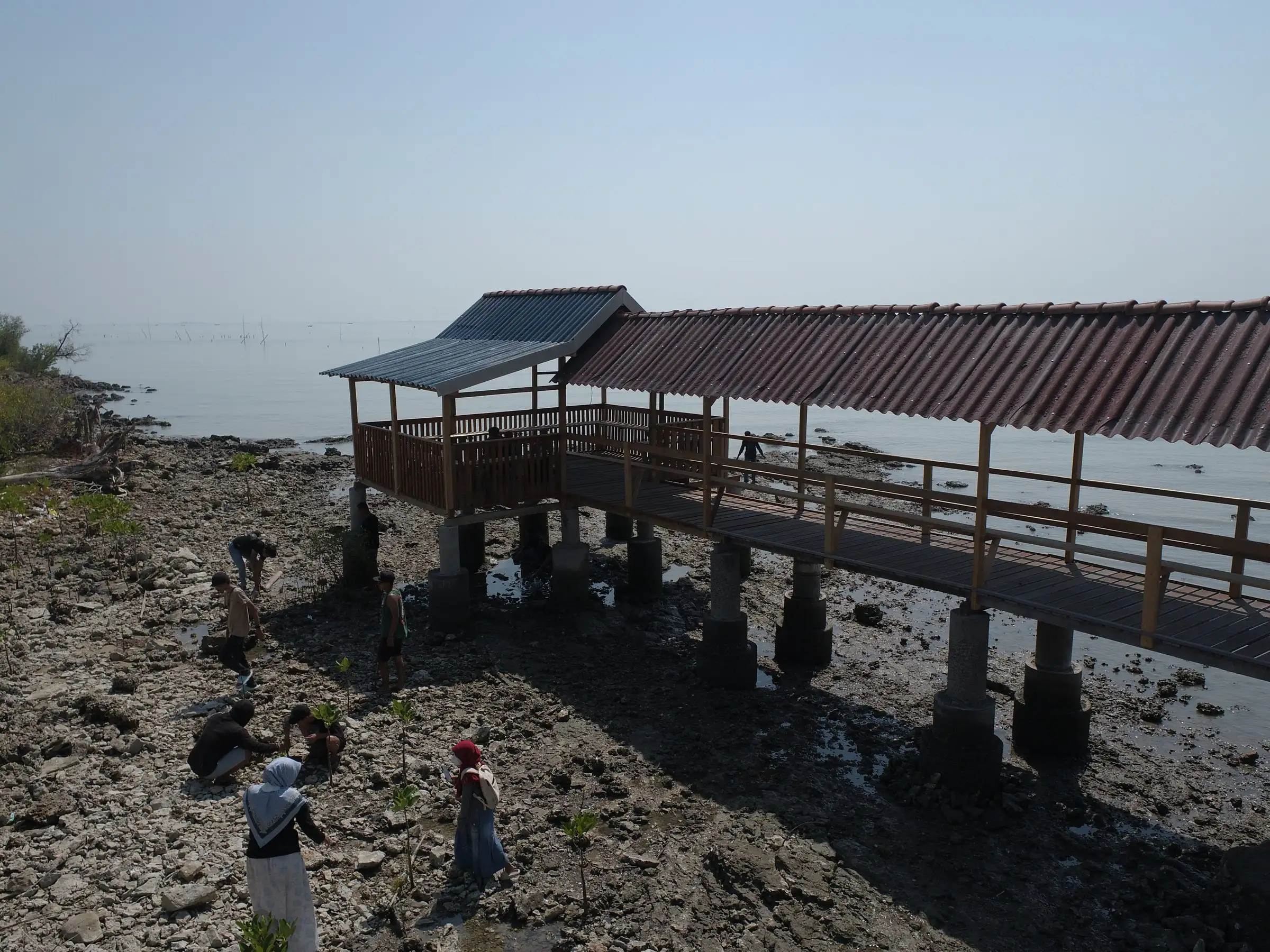 Bangunan pantau beratap di tepi pantai berbatu saat surut