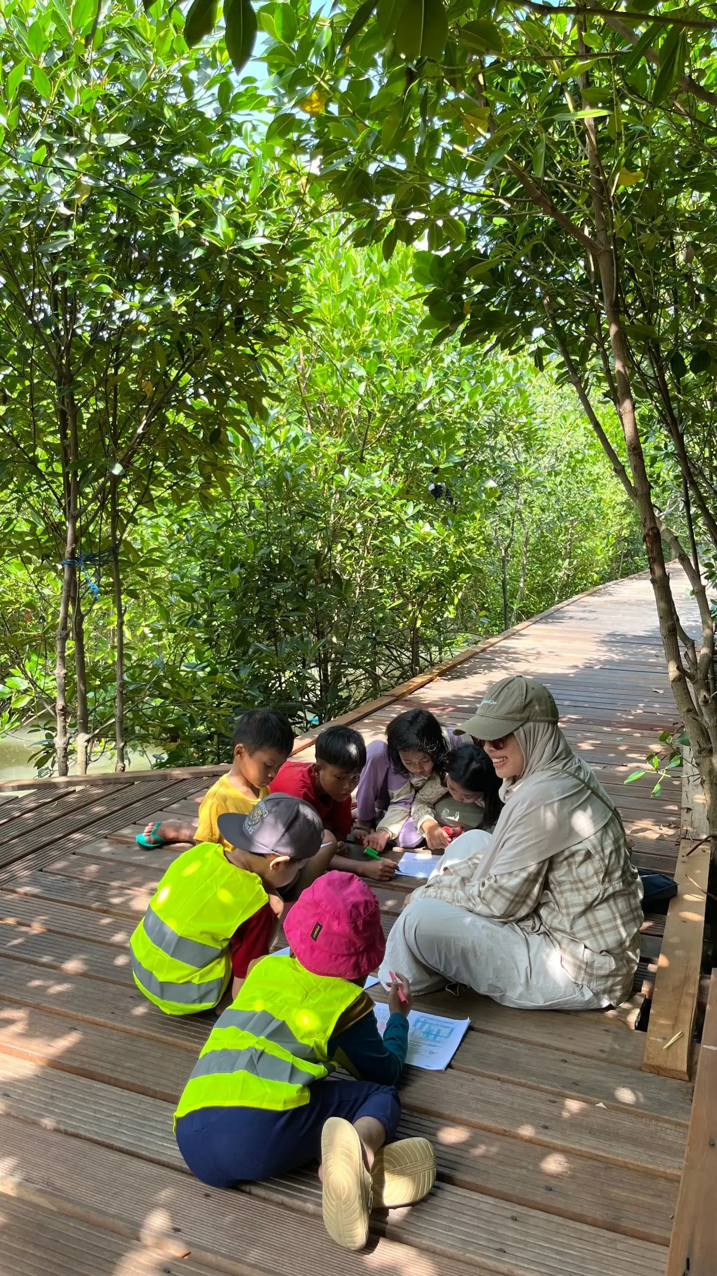 Anak-anak mengerjakan lembar kerja bersama fasilitator di jembatan pemantauan mangrove