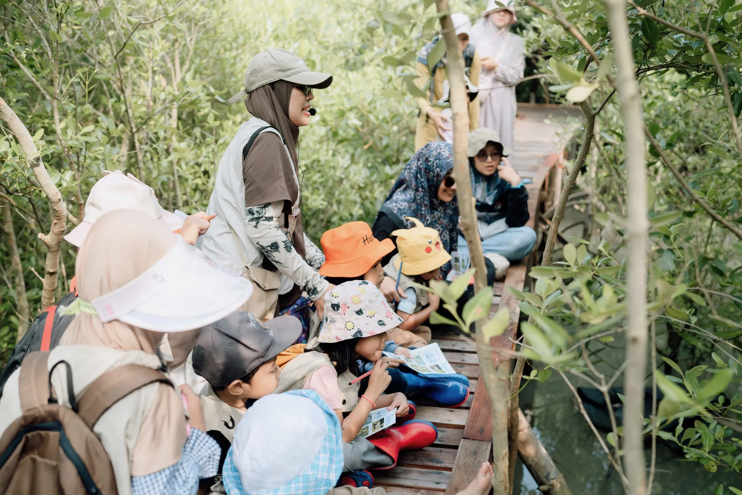 Anak-anak dan fasilitator berhenti di jembatan pemantauan untuk mengamati mangrove