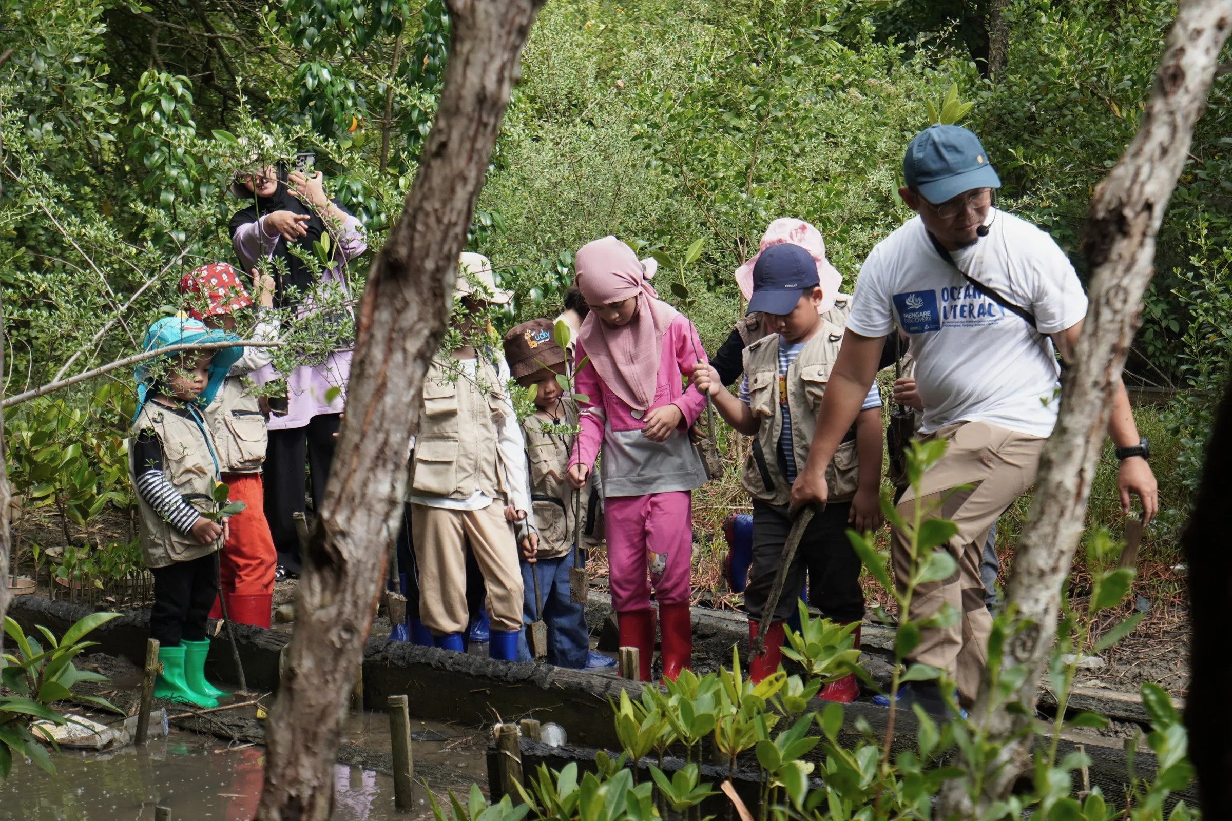 Pemandu menjelaskan bibit mangrove kepada anak-anak di sela mangrove, 13 Juli 2025