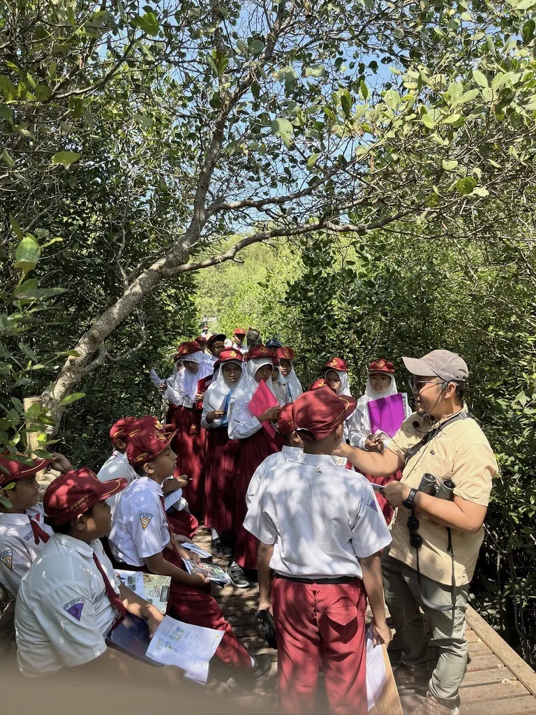 Siswa sekolah dasar mendengarkan pemandu di jembatan pemantauan mangrove