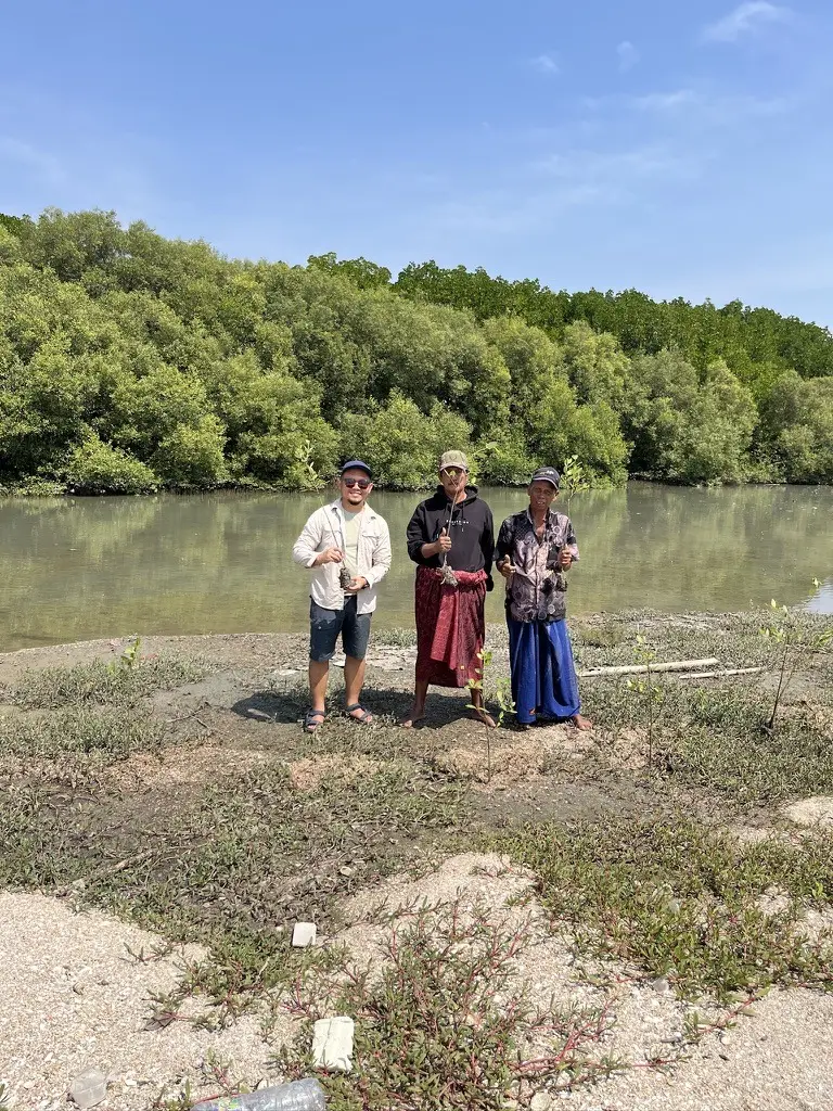 Warga memegang bibit mangrove di tepi sungai sebelum ditanam